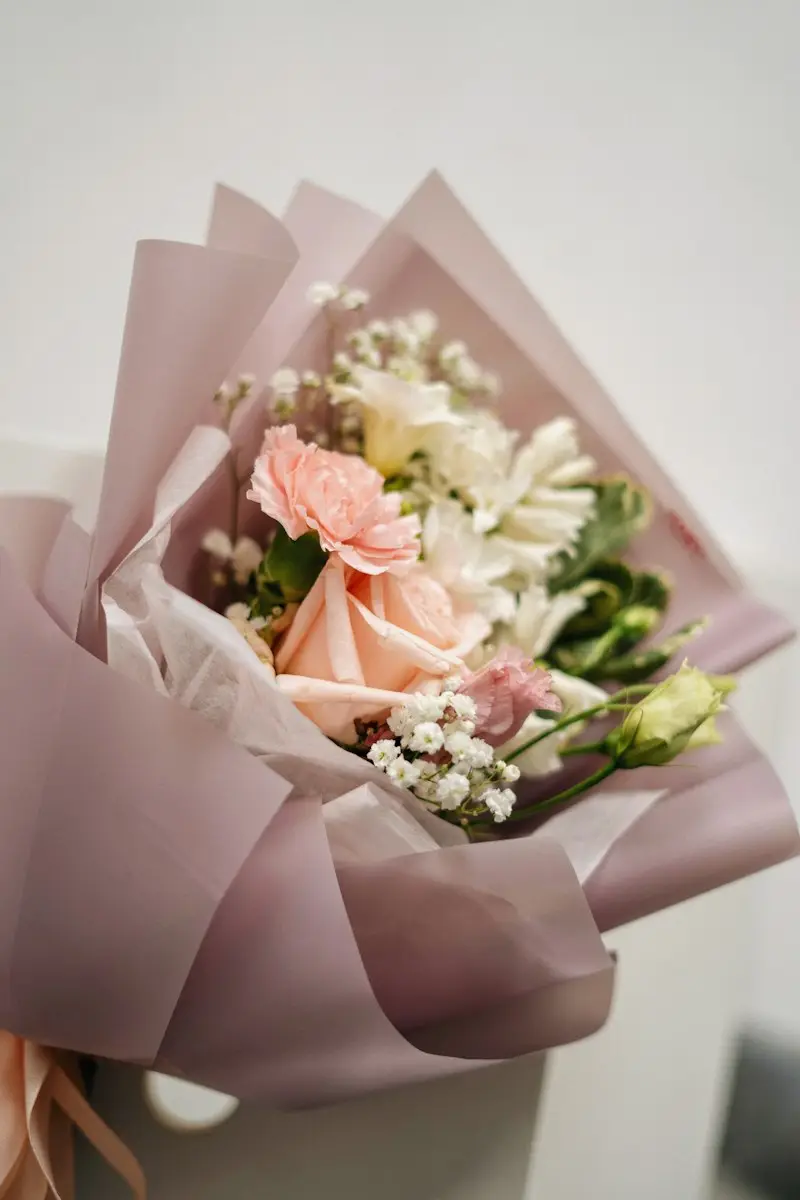 ピンクの紙で包んだ季節の花束